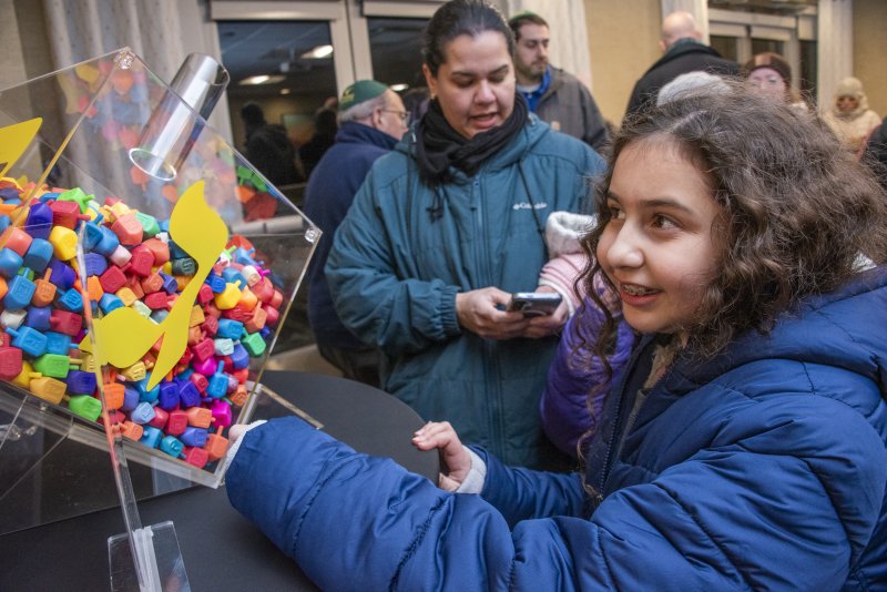Sarah Fisher of Millsboro makes her best guess at the number of dreidels in the dreidel container while her mom Christine uploads the count to the app. DENY HOWETH PHOTOS
